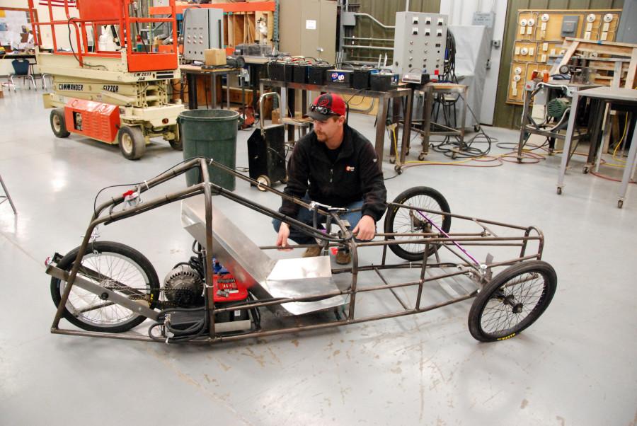 Northeast Community College student Travis Wheeler, of Wood Lake, looks over an electric car that he and other students worked on this past semester. The project actually began in 2007 when  electrical construction and control students built the frame for the vehicle. (Courtesy Photo)