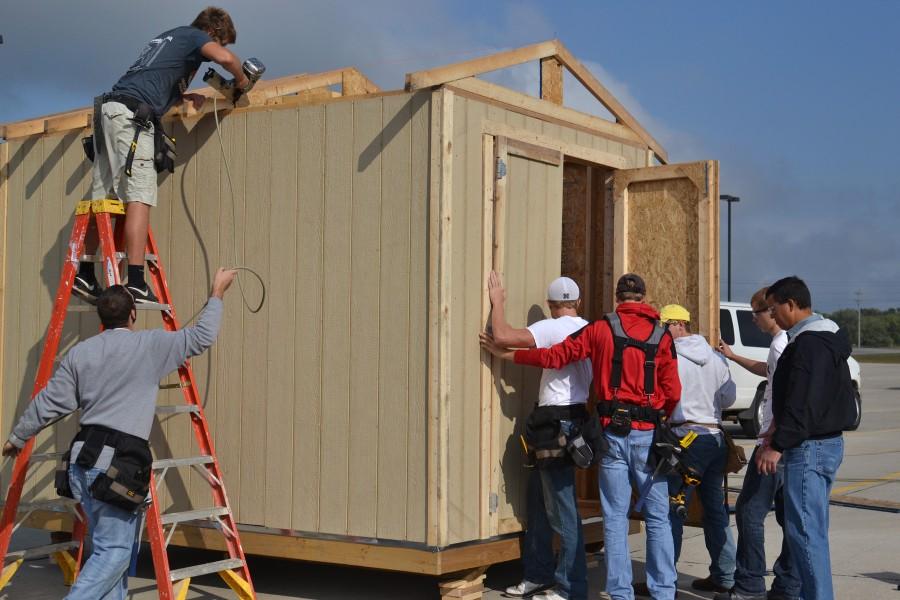 Ryan Hobza (right), building construction instructor at Northeast Community College, oversees members of his freshman class as they construct a shed at First Christian Church in Norfolk. The church accepted the help from the students to construct two of the sheds, which will be sent to Pilger along with several others. First Christian is providing the sheds to victims of a June 16 tornado who plan to rebuild their homes in the Stanton County village. (Courtesy First Christian Church)