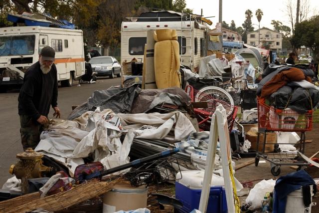 Armon Coleman, 63, looks over his belongings, left, at his homeless encampment along W. 94th Street in the Manchester Square neighborhood on Jan. 4, 2017 in Los Angeles. LAX has bought much of the property from homeowners over the past years and will eventually build a rental car facility at the site. In the meantime, the homeless are sleeping on sidewalks outside the fenced lots that are owned by LAX. (Genaro Molina/Los Angeles Times/TNS)