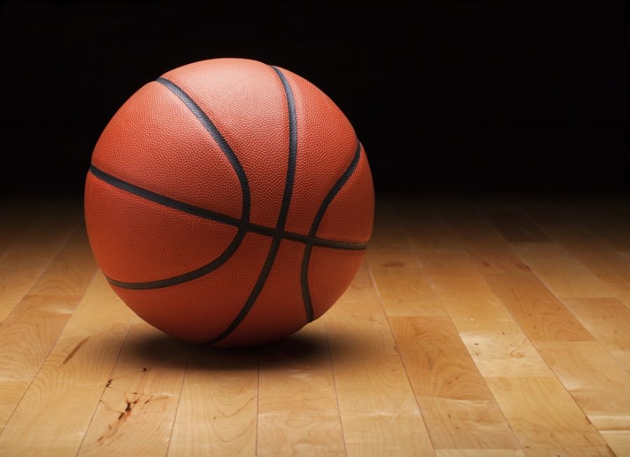 A+basketball+with+a+dark+background+on+a+hardwood+gym+floor